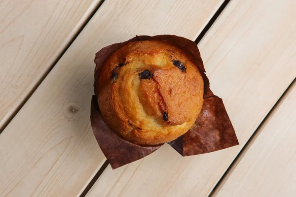 Draufsicht auf frischen Muffin mit Schokoladenstücken in Papierfolie o — Stockfoto