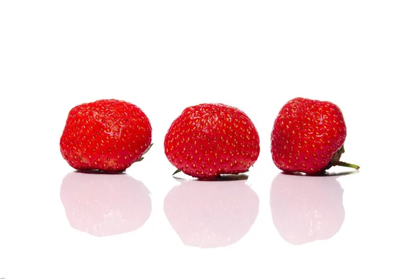 Tre färska jordgubbar från trädgård säng med reflektion på glas isolerade på vit bakgrund — Stockfoto