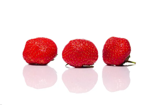 Tres fresas frescas de cama de jardín con reflexión sobre vidrio aislado sobre fondo blanco — Foto de Stock