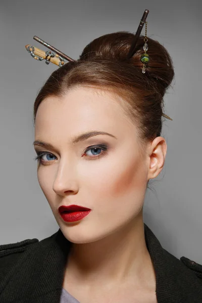 Portrait of model with oriental hairstyle, red lips and blue eye