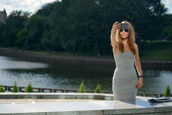Aantrekkelijke toeristische meisje selfie met rivieroever op achtergrond maken in stadspark — Stockfoto
