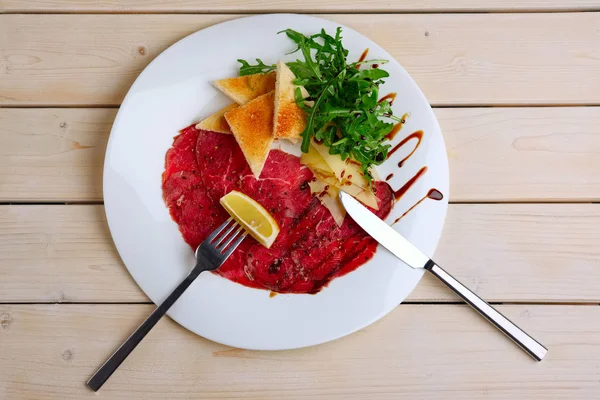 Bovenaanzicht van de plaat met Rundercarpaccio met kaas, wit brood, toast en citroen op vork — Stockfoto