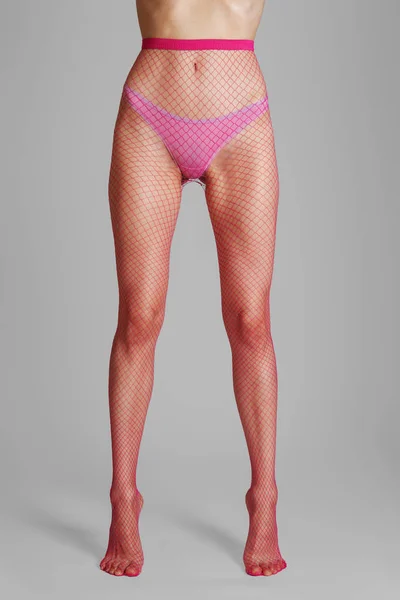 Μακρύ μυϊκό γυναικεία πόδια σε σέξι ροζ δικτυωτό καλσόν. Μπροστινή όψη. — Φωτογραφία Αρχείου