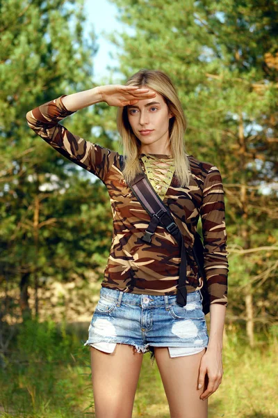 Attraktives Mädchen im Camo-Hemd, Jeans-Shorts mit Rucksack auf Wanderweg im Wald — Stockfoto