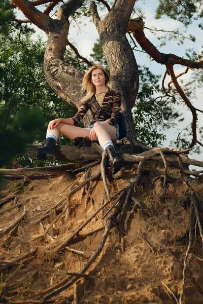 Menina turística atraente sentado na raiz da árvore — Fotografia de Stock