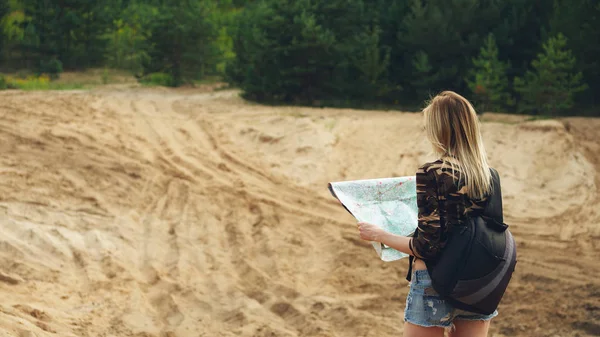 Back side of traveler girl searching right direction on map