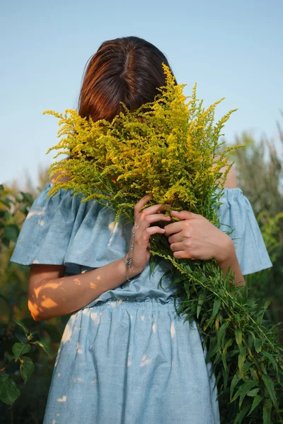 Mooi meisje verborgen gezicht in veld bloemen — Stockfoto