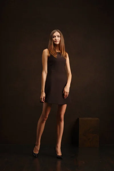 Привлекательная девушка в коротком платье позирует возле темной стены в провокационной манере — стоковое фото