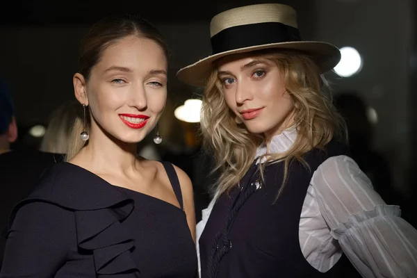 Two pretty models posing to camera at backstage of fashion week