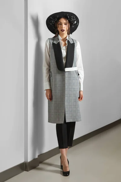 Hübsches Mode-Model in ärmelloser Jacke, Hose, Hemd und breitem Hut mit Blumen — Stockfoto