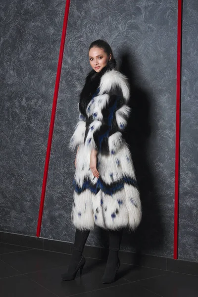 Chica atractiva en largo abrigo de piel bouffant posando cerca de la pared helada fría — Foto de Stock