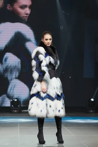 Hermosa modelo de moda camina en la pasarela en abrigo de piel con pantalla en línea en el fondo — Foto de Stock