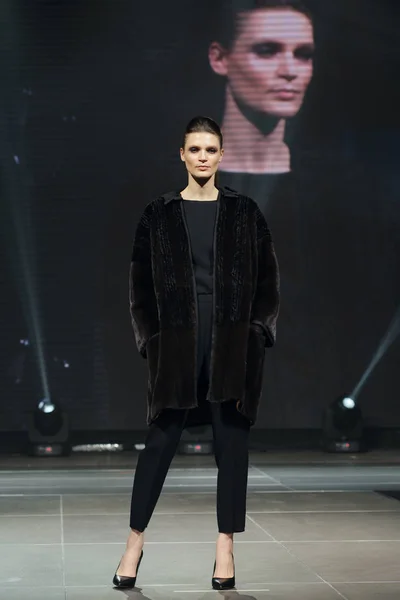 Hermosa modelo de moda camina en la pasarela en abrigo de piel con pantalla en línea en el fondo — Foto de Stock