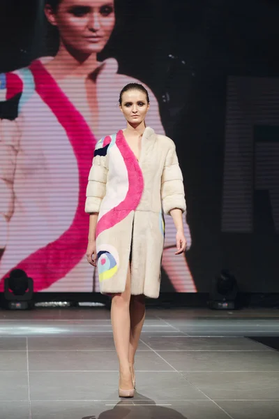 Hermosa modelo de moda camina en la pasarela en abrigo de piel con pantalla en línea en el fondo — Foto de Stock