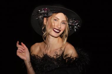 Siyah arka plan üzerine çiçekli boa ve geniş ağzına kadar şapka ile siyah elbiseli güzel kız closeup portresi