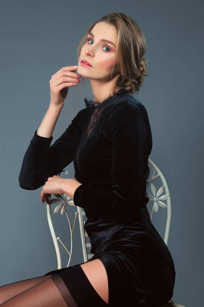 Sandalyede oturan derin kesik ile uzun kadife elbiseli güzel Bayan — Stok fotoğraf