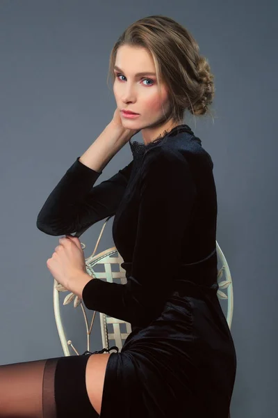 Sandalyede oturan derin kesik ile uzun kadife elbiseli güzel Bayan — Stok fotoğraf