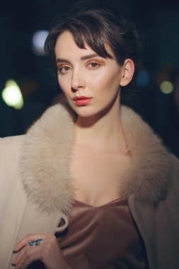 Kürk yaka arka plan ışık ile karanlık odada poz ile paltolu güzel kız portresi