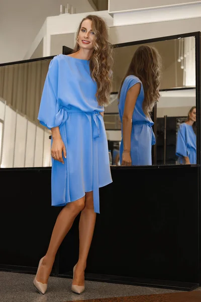 Mooi meisje in hemelsblauw jurk in de buurt van spiegel met meervoudige reflecties — Stockfoto