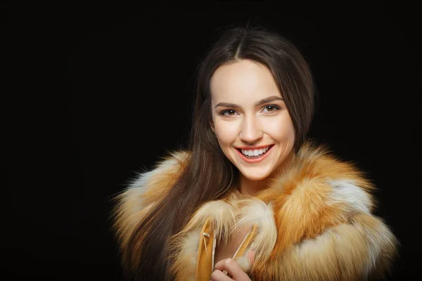 Retrato de bela menina feliz com maquiagem natural em casaco de pele macia no fundo preto — Fotografia de Stock