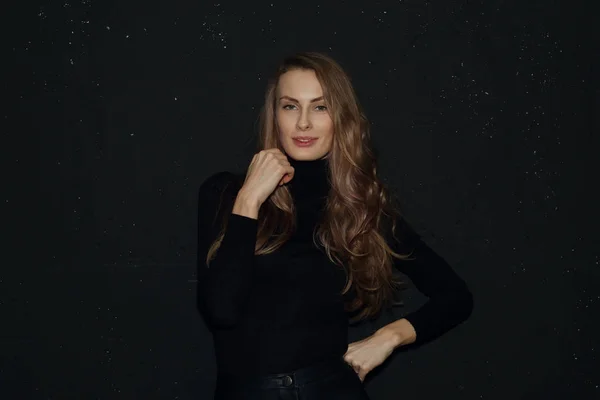 Menina bonito em preto jumper perto de parede preta em pontos no fundo — Fotografia de Stock