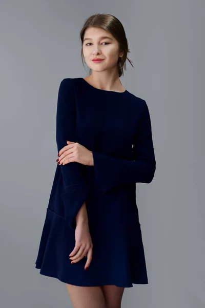 Retrato de foco suave de chica bonita en vestido azul corto posando sobre fondo gris. En blanco para un diseño . — Foto de Stock