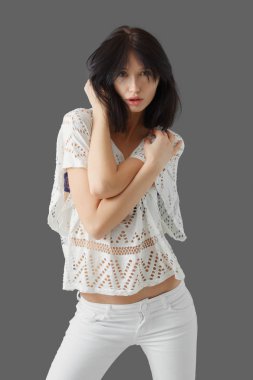 Modeli sınama güzel moda model gri arka plan üzerinde poz portresi. Dantel bluz saç ile oynayan kız.