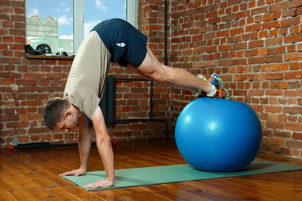 Homem atlético fazendo exercícios de equilíbrio com a bola de ginástica — Fotografia de Stock
