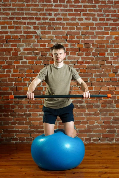 Hombre atlético haciendo ejercicios para el equilibrio en la pelota de goma con — Foto de Stock