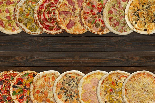 Horizontální koláž různých pečené pizzy na tmavý dřevěný stůl. Pohled shora. — Stock fotografie