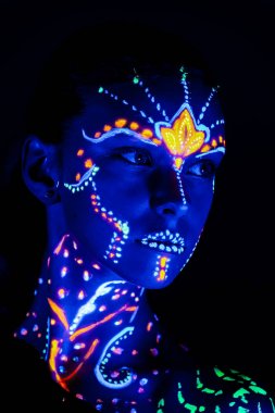 Portrait of beautiful girl with ultraviolet paint on her face. Girl with neon make-up in color light. clipart