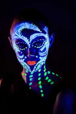Yüzünde ultraviyole boya ile güzel kız portresi. Renk ışık neon makyajlı kız.
