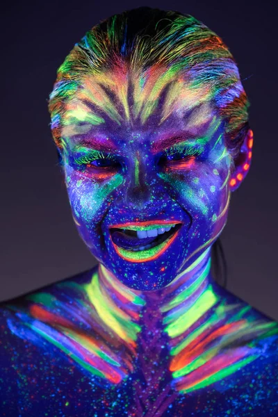 Portrait de belle fille avec de la peinture ultraviolette sur le visage. G — Photo