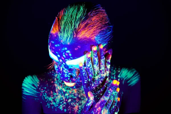 Portrait of beautiful girl with ultraviolet paint on her face. Girl with neon make-up in color light.