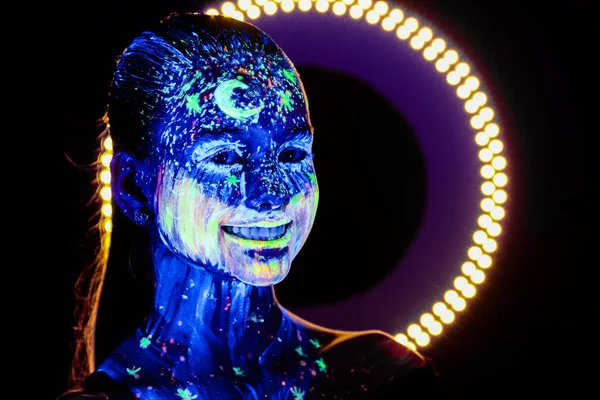 Retrato de una hermosa chica con pintura ultravioleta en su cara. Chica con maquillaje de neón en luz de color . —  Fotos de Stock