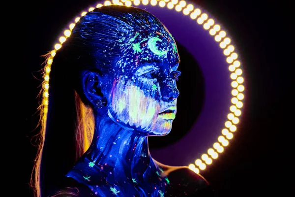 Portrait de belle fille avec de la peinture ultraviolette sur le visage. Fille avec néon maquillage dans la lumière de couleur . — Photo