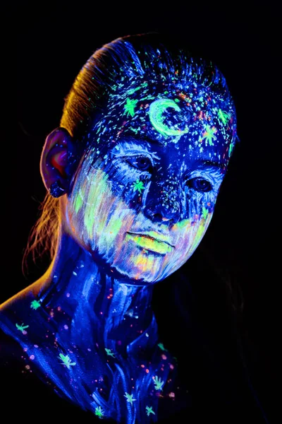 Portrait de belle fille avec de la peinture ultraviolette sur le visage. Fille avec néon maquillage dans la lumière de couleur . — Photo