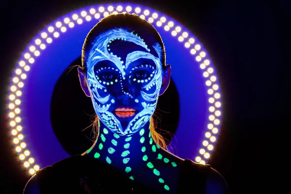 Retrato de una hermosa chica con pintura ultravioleta en su cara. Chica con maquillaje de neón en luz de color . —  Fotos de Stock