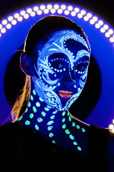 Retrato de una hermosa chica con pintura ultravioleta en su cara. Chica con maquillaje de neón en luz de color . —  Fotos de Stock