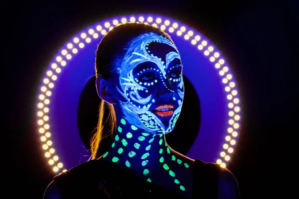 Retrato de una hermosa chica con pintura ultravioleta en su cara. Chica con maquillaje de neón en luz de color . —  Fotos de Stock