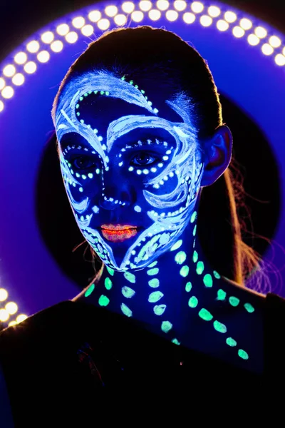 Retrato de una hermosa chica con pintura ultravioleta en su cara. Chica con maquillaje de neón en luz de color . —  Fotos de Stock