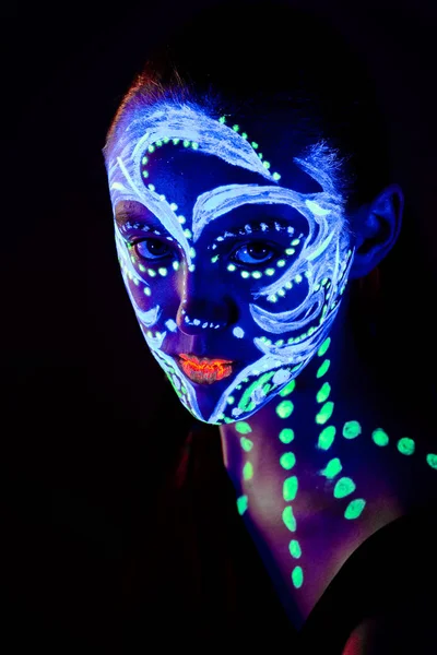 Retrato de una hermosa chica con pintura ultravioleta en su cara. Chica con maquillaje de neón en luz de color . —  Fotos de Stock