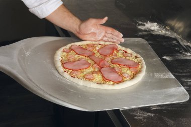 Fırında pişirme için metal kürek ile ham pizza alarak