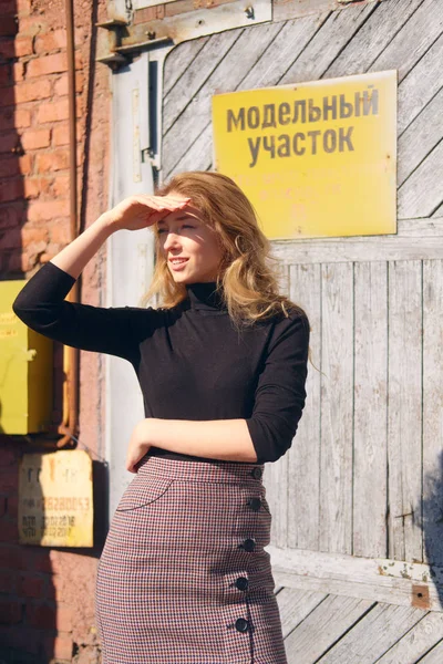 Attraktives Mädchen in der Nähe der Fabriktür mit Warnschildern, die die Augen mit der Hand bedecken — Stockfoto