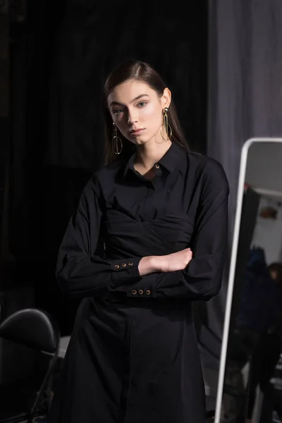 Mooi meisje in een zwarte jurk in kleedkamer in de buurt van de spiegel — Stockfoto