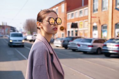 Genç kız karşıdan karşıya geçerken. Sokak içinde yansıtan ile ayna güneş gözlüğü.