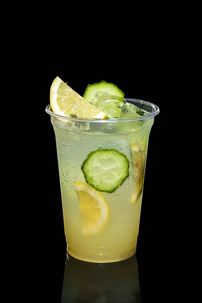 Cold Lemon and cucumber cocktail with a sparkling wine with ice cubes in take away glass isolated on black — Stock Photo, Image