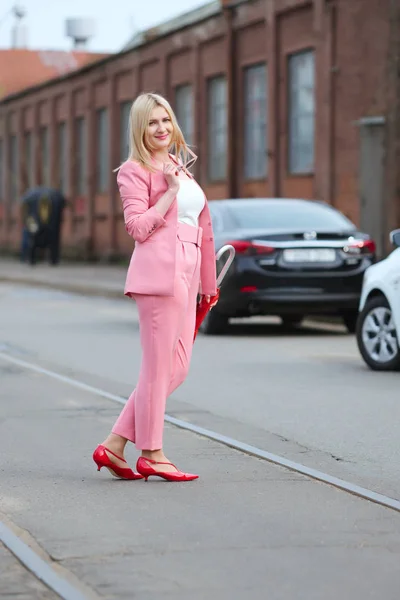 Mujer en traje rosa y con paraguas cruzando la calle — Foto de Stock