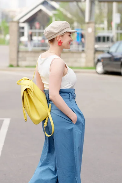 Девушка в квадратной шляпе, белый t shrt и синие широкие брюки ходьба на парковке автомобиля — стоковое фото