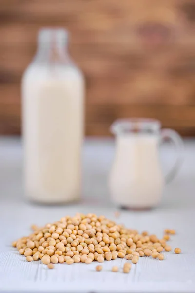 Bouteille et pichet de lait de soja sur table blanche — Photo